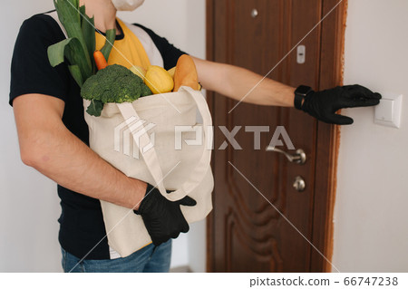 Delivery man in mask and gloves bring fresh food to customer's home. Stay home. Online shopping concept. Middle selection Delivery man in mask and gloves bring fresh food to customer's home. Stay home. Online shopping concept. Middle selection 66747238