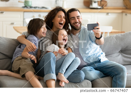 Close up happy parents with little children using smartphone together. Close up happy parents with little children using smartphone together. 66747407