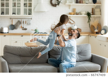 Adorable preschool son flying with hands outstretched in caring father. 66747409