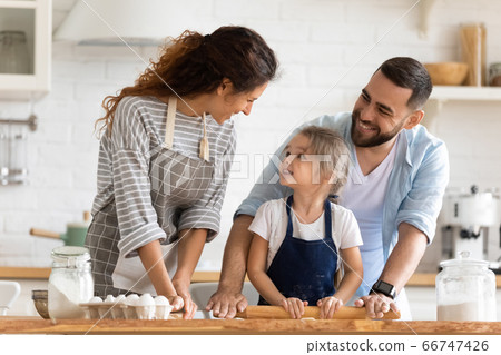 Mother and father teaching little daughter to cooking pastry. Mother and father teaching little daughter to cooking pastry. 66747426