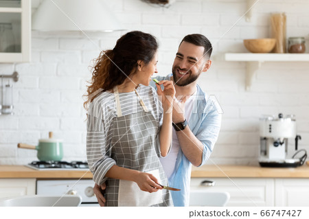 Close up happy couple playfully cooking cooking salad in kitchen. 66747427
