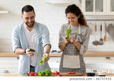Happy couple laughing holding green cucumber in hands. Happy couple laughing holding green cucumber in hands. 66747438