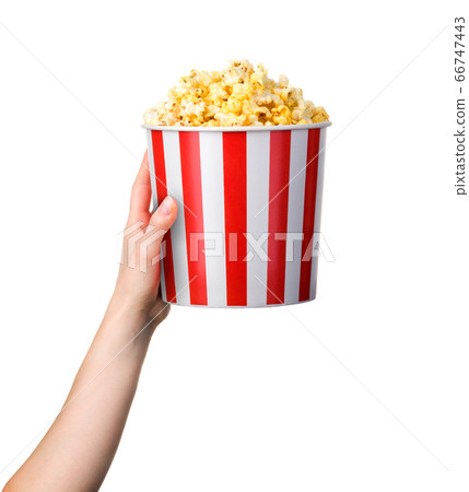 Woman hand holding striped bucket with popcorn Woman hand holding striped bucket with popcorn 66747443