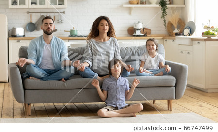 Relaxed young family with cute children sitting and meditating. 66747499