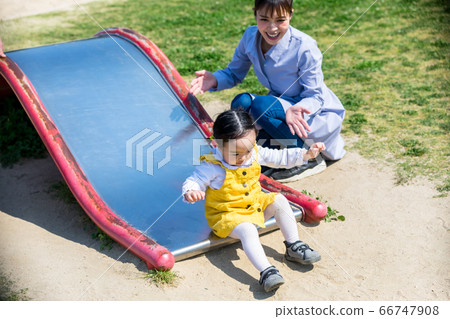 父母和孩子在公園的幻燈片上玩 父母和孩子在公園的幻燈片上玩 66747908