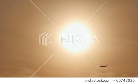 Take off the plane in the distance against the background of sunrise or sunset. Silhouette of an airplane. Airplane in the sky at sunset. Take off the plane in the distance against the background of sunrise or sunset. Silhouette of an airplane. Airplane in the sky at sunset. 66748036