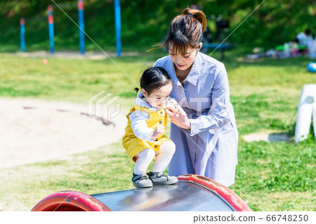 Infant and mom playing on a slide in the park Infant and mom playing on a slide in the park 66748250