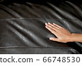 The woman's hand touching the surface of the sofa. 66748530