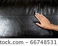 The woman's hand touching the surface of the sofa. 66748531