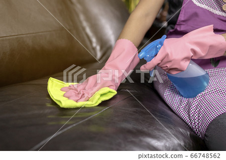 Woman wipe sofa with germicidal spray and wipe with towel. Woman wipe sofa with germicidal spray and wipe with towel. 66748562