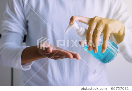 Women hands holding sanitizer gel in pump bottle for hand hygiene coronavirus protection in bedroom 66757081