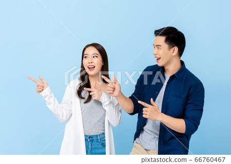 Smiling Asian couple tourists pointing to empty space 66760467