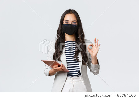 Business, finance and employment, covid-19 preventing virus and social distancing concept. Asian businesswoman with digital tablet, wear protective mask against virus and showing okay sign 66764169