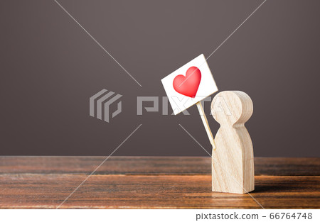 A man with a red heart on sign. Active search for a partner for dating. Sympathy and love, express support, like. Celebrating Valentine's Day. Online dating, relationship building. Give preference 66764748