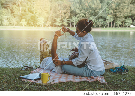 Asian couple lover sitting a relax River side in the public park. working with a notebook 66765272