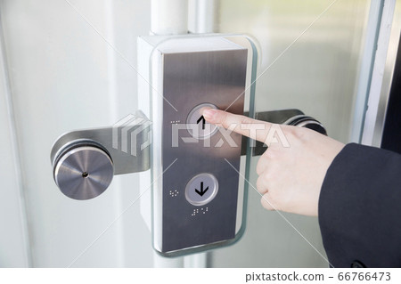 Young woman pushing the button of the elevator 66766473