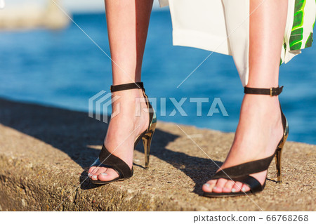Woman feet in high heels shoes on sea pier Woman feet in high heels shoes on sea pier 66768268