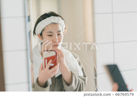 一個女人看著智能手機時刷牙 66769579