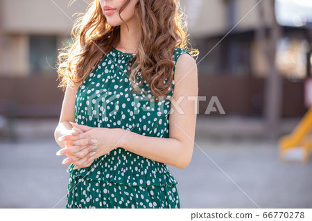 一個穿著綠色衣服的女人站在外面的衣服漂亮的頭髮 66770278