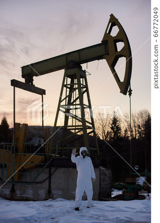 Ecologist standing near oil well pump jack. Ecologist standing near oil well pump jack. 66772049