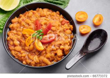 Ful Medames or Fava Beans in black bowl at grey backdrop. Foul Mudammas is a Egyptian cuisine dish Ful Medames or Fava Beans in black bowl at grey backdrop. Foul Mudammas is a Egyptian cuisine dish 66773372