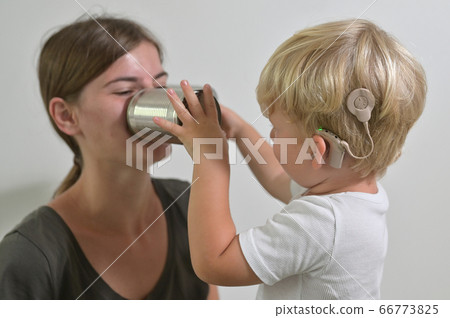 Boy with Cochlear Implants Playing Tin Can Phone 66773825