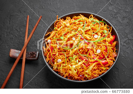 Chinese Bhel in bowl on black table top. Indo-Chinese cuisine street food dish with schezwan sauce Chinese Bhel in bowl on black table top. Indo-Chinese cuisine street food dish with schezwan sauce 66773880