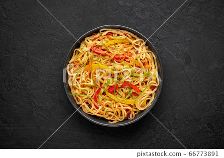 Chilli Garlic Hakka Noodles in bowl on black slate table top. Indo-Chinese vegetarian cuisine dish. 66773891