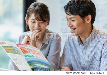 Men and women making plans while looking at travel brochures 66776671