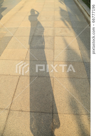 Long shadow of woman figure, taking photograph, on Long shadow of woman figure, taking photograph, on 66777196