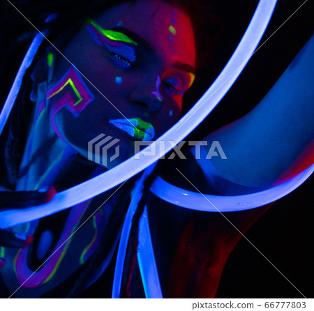 Portrait of a Warror Girl with Glowing Tubes in Neon UF Light. Model Girl with Dreadlocks and Fluorescent Creative Psychedelic MakeUp, Art Design of Female Disco Dancer Model in UV, Colorful Abstract Portrait of a Warror Girl with Glowing Tubes in Neon UF Light. Model Girl with Dreadlocks and Fluorescent Creative Psychedelic MakeUp, Art Design of Female Disco Dancer Model in UV, Colorful Abstract 66777803