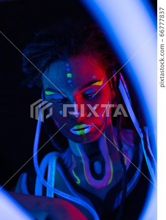 Portrait of a Warror Girl with Glowing Tubes in Neon UF Light. Model Girl with Dreadlocks and Fluorescent Creative Psychedelic MakeUp, Art Design of Female Disco Dancer Model in UV, Colorful Abstract Portrait of a Warror Girl with Glowing Tubes in Neon UF Light. Model Girl with Dreadlocks and Fluorescent Creative Psychedelic MakeUp, Art Design of Female Disco Dancer Model in UV, Colorful Abstract 66777837