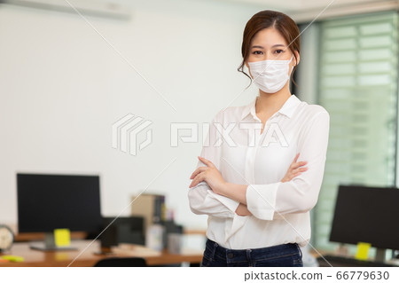 Asian business women leader wearing mask protection virus standing smile cross arm and confidence at Co-Working space Due Covid-19 Flu Pandemic,Health care and Business Startup Concept 66779630