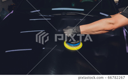 Car detailing - Hands with orbital polisher in auto repair shop. Selective focus. Car detailing - Hands with orbital polisher in auto repair shop. Selective focus. 66782267