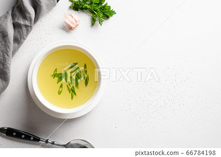 Chicken broth with green onion in white bowl on white table. Copy space. Top view. 66784198