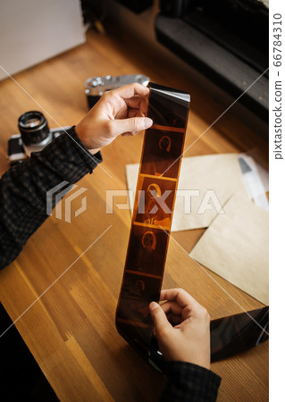 man is examines a medium format film. Vintage old 66784310