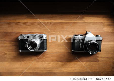 Two retro film cameras lie on a wooden table 66784332