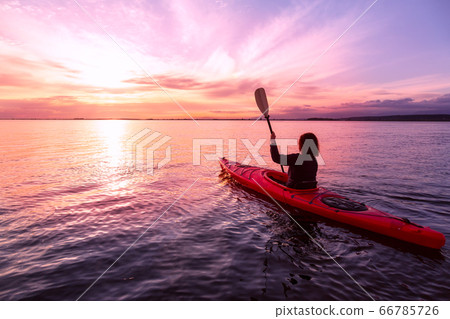Sea Kayaking in calm waters during a colorful and vibrant sunset. Sea Kayaking in calm waters during a colorful and vibrant sunset. 66785726