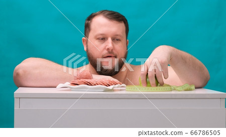 bearded fat man chooses between a sausage or a green apple on a green screen. Man chooses healthy 66786505