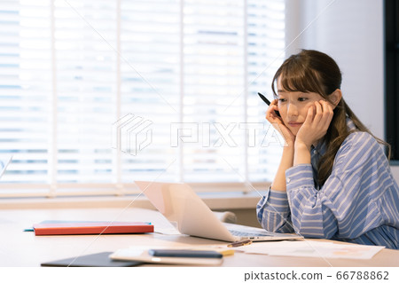 A young woman teleworking towards a computer [tired] 66788862