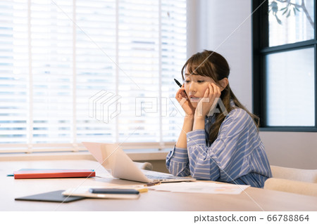A young woman teleworking towards a computer [tired] 66788864