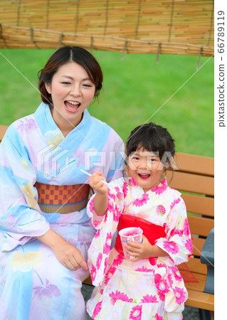 Girl in yukata, wearing yukata, eating shaved ice outdoors 66789119
