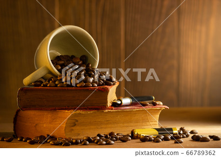 Coffee bean in the white cup and vintage book stacking on wooden table in morning light. Coffee bean in the white cup and vintage book stacking on wooden table in morning light. 66789362