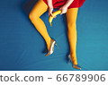 Women legs in yellow tights and a red skirt with a banana in their hands on a blue background 66789906