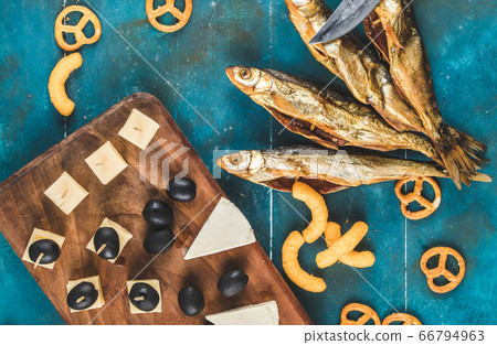 Dry fish snack with cheese, olive and crackers on the blue table, on a wooden board Dry fish snack with cheese, olive and crackers on the blue table, on a wooden board 66794963