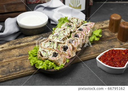 Roll salad in lavash bread on a lettuce leaf served with tomato paste Roll salad in lavash bread on a lettuce leaf served with tomato paste 66795162