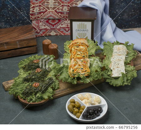 Green herbal omlette on a lettuce leaf on a wooden board served with cheese and olives Green herbal omlette on a lettuce leaf on a wooden board served with cheese and olives 66795256