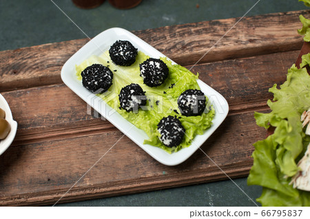 Cheese rolls with black spices on a lettuce leaf. Cheese rolls with black spices on a lettuce leaf. 66795837