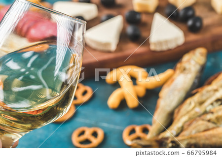 Snack board with cheese cubes, cracker, a glass of wine and dry fish Snack board with cheese cubes, cracker, a glass of wine and dry fish 66795984