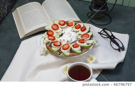 Waffles with sliced banana, strawberries and whipping cream 66796797